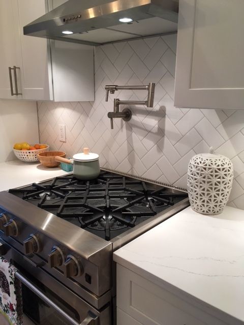 Design ideas for a traditional galley kitchen in Philadelphia with a farmhouse sink, shaker cabinets, white cabinets, white splashback, subway tile splashback, stainless steel appliances, medium hardwood floors and marble benchtops.