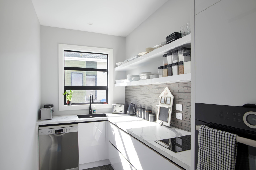 Idéer för ett avskilt, mellanstort modernt vit l-kök, med vita skåp, marmorbänkskiva, grått stänkskydd, rostfria vitvaror, marmorgolv, en köksö och brunt golv