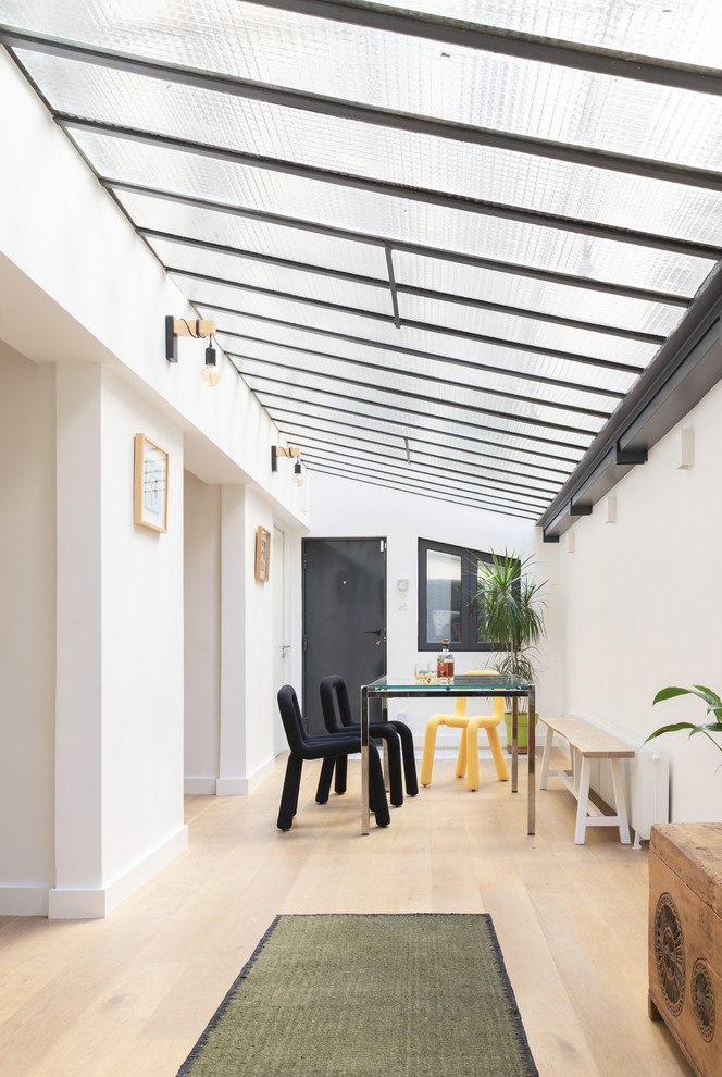 Réalisation d'une grande salle à manger urbaine avec un mur blanc et parquet clair.