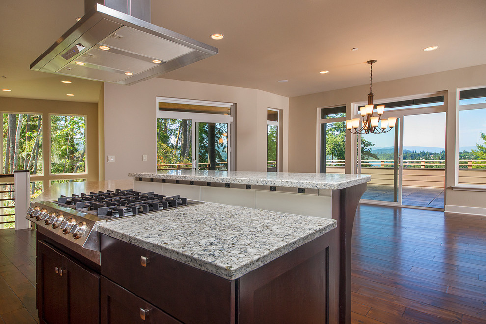 Large transitional l-shaped medium tone wood floor eat-in kitchen photo in Seattle with shaker cabinets, dark wood cabinets, granite countertops, white backsplash, glass tile backsplash, stainless steel appliances and two islands