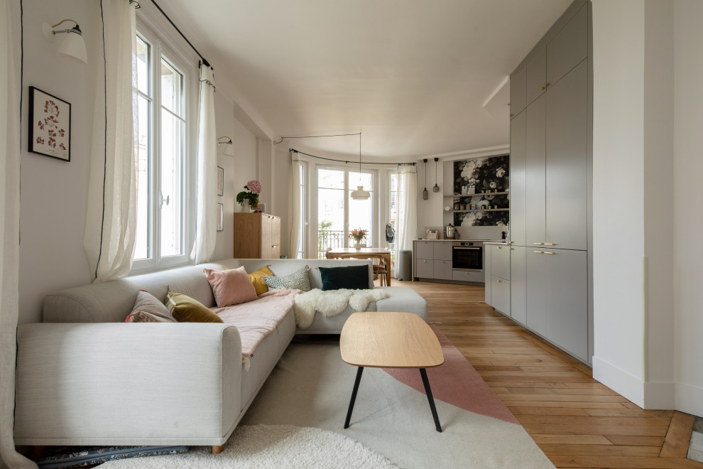 This is an example of a mid-sized scandinavian open concept family room in Paris with white walls, light hardwood floors, no fireplace, no tv and beige floor.