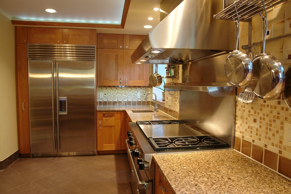 This is an example of a mid-sized traditional u-shaped eat-in kitchen in Baltimore with shaker cabinets, medium wood cabinets, mosaic tile splashback, stainless steel appliances, an undermount sink, quartz benchtops, brown splashback, with island and brown floor.
