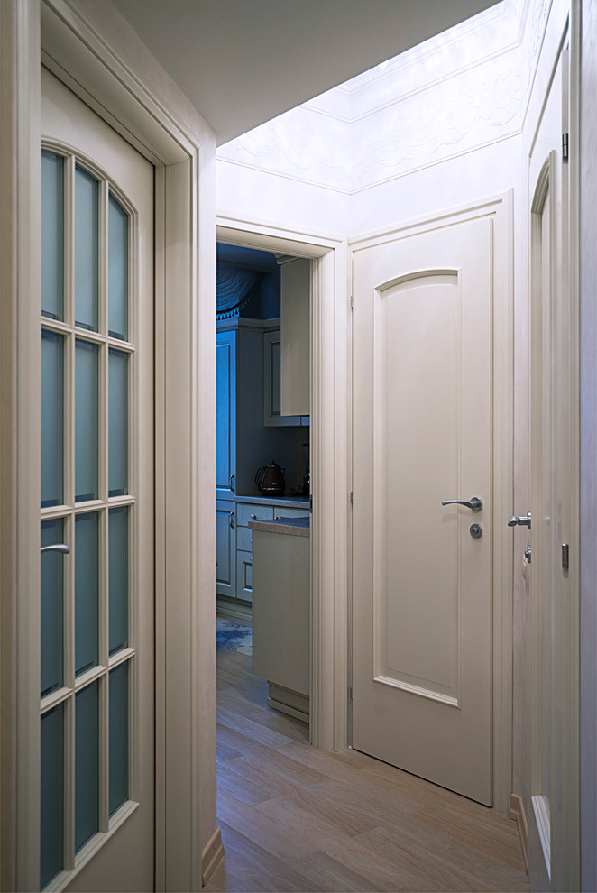 This is an example of a small traditional hallway in Moscow with beige walls and light hardwood floors.