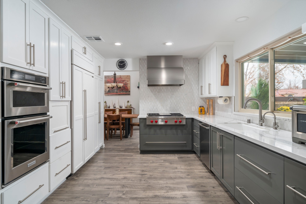 Medium sized modern u-shaped kitchen/diner in Los Angeles with a submerged sink, shaker cabinets, white cabinets, engineered stone countertops, white splashback, marble splashback, stainless steel appliances, vinyl flooring, an island, grey floors and white worktops.