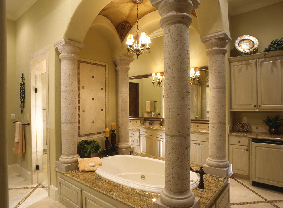 Inspiration for an expansive mediterranean master bathroom in Houston with an undermount sink, raised-panel cabinets, beige cabinets, granite benchtops, beige tile, terra-cotta tile, beige walls and terra-cotta floors.