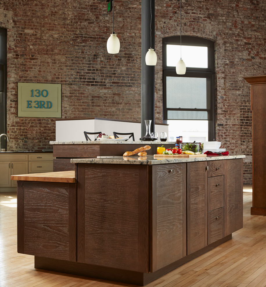 Mid-sized industrial u-shaped eat-in kitchen in Other with dark wood cabinets, quartz benchtops, stainless steel appliances, light hardwood floors, with island, brown floor, an undermount sink, flat-panel cabinets, red splashback and brick splashback.
