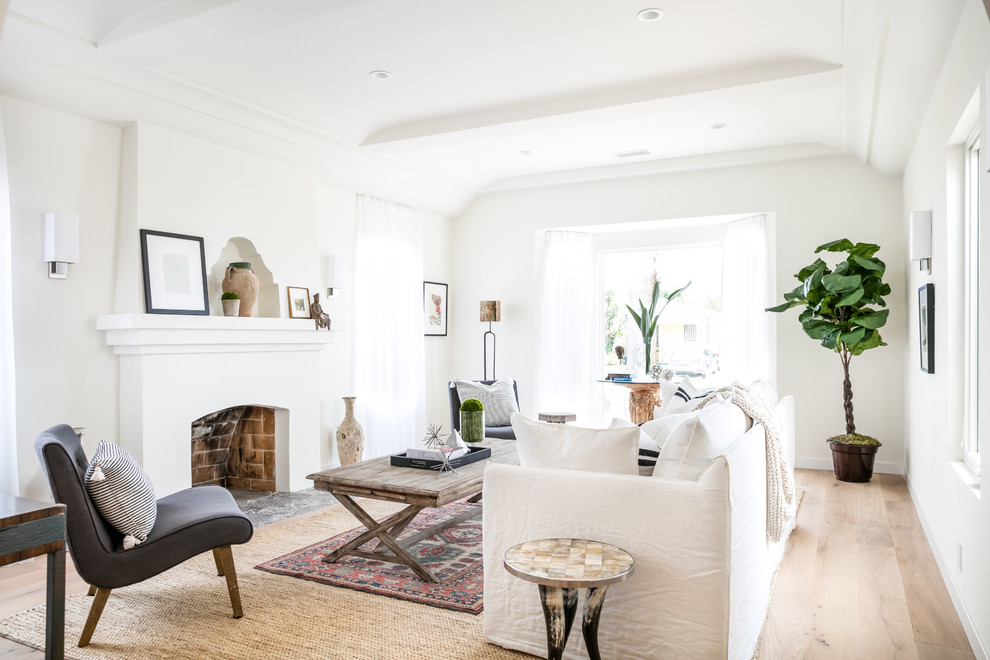 Photo of a transitional living room in Los Angeles with white walls, medium hardwood floors and a standard fireplace.