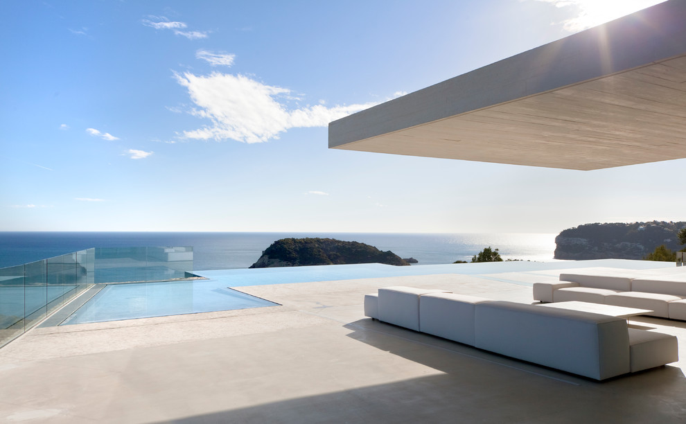 Expansive contemporary backyard custom-shaped infinity pool in Alicante-Costa Blanca with concrete slab.