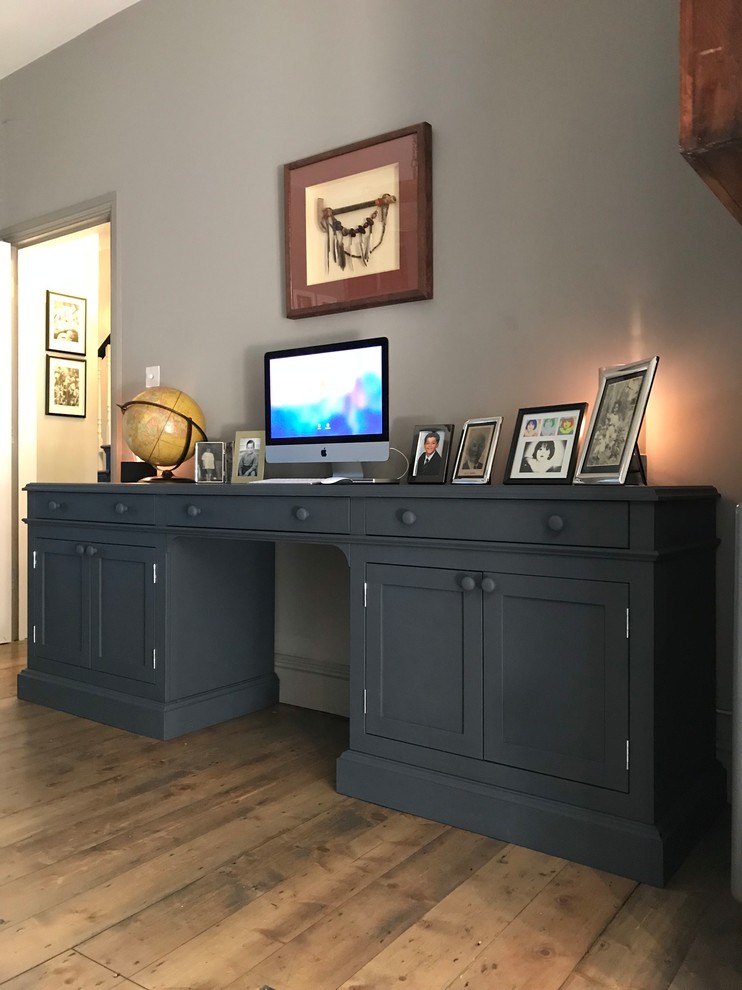Design ideas for a large traditional study room in London with grey walls, medium hardwood floors, a standard fireplace, a metal fireplace surround, a freestanding desk and brown floor.