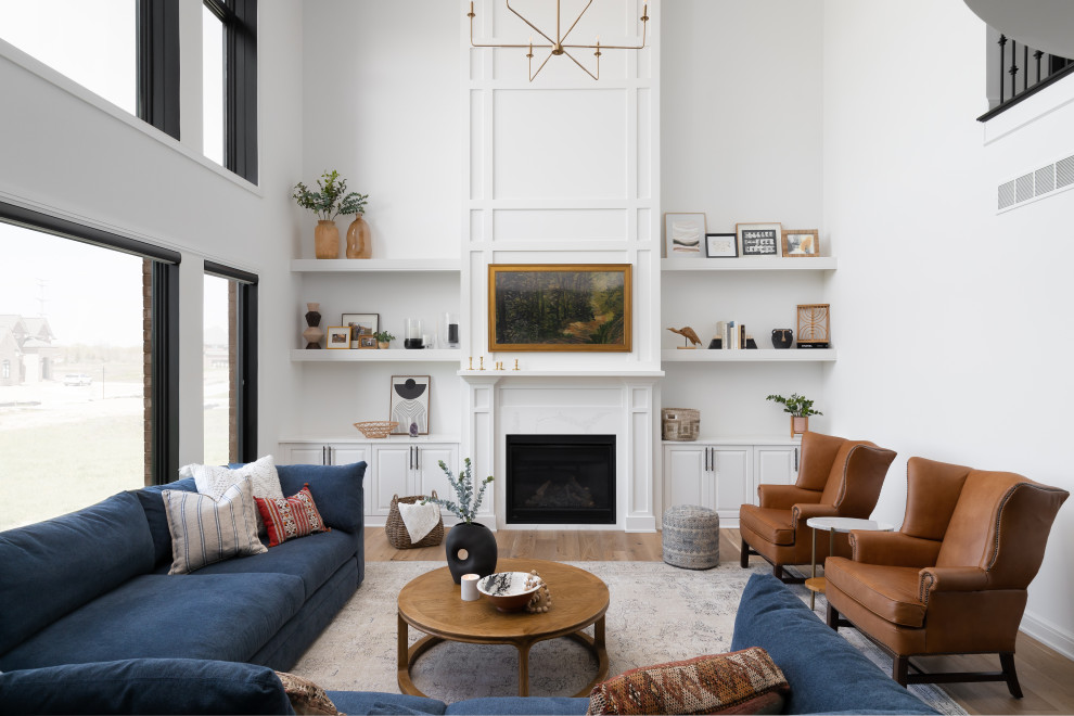 This is an example of a large transitional open concept living room in Detroit with white walls, light hardwood floors, a standard fireplace, a wood fireplace surround, a wall-mounted tv, vaulted and decorative wall panelling.