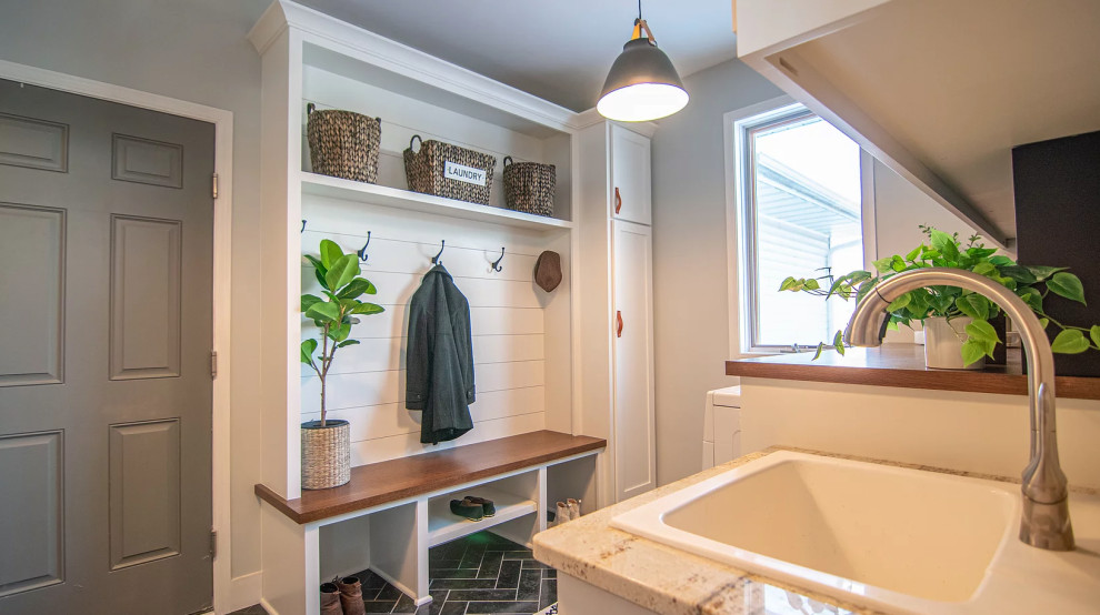 Mid-sized transitional laundry room in Minneapolis with an utility sink, shaker cabinets, white cabinets, wood benchtops, slate splashback, slate floors, a side-by-side washer and dryer, black floor and brown benchtop.