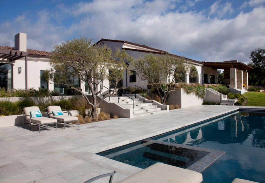 This is an example of a large mediterranean backyard rectangular natural pool in San Diego with a pool house and natural stone pavers.