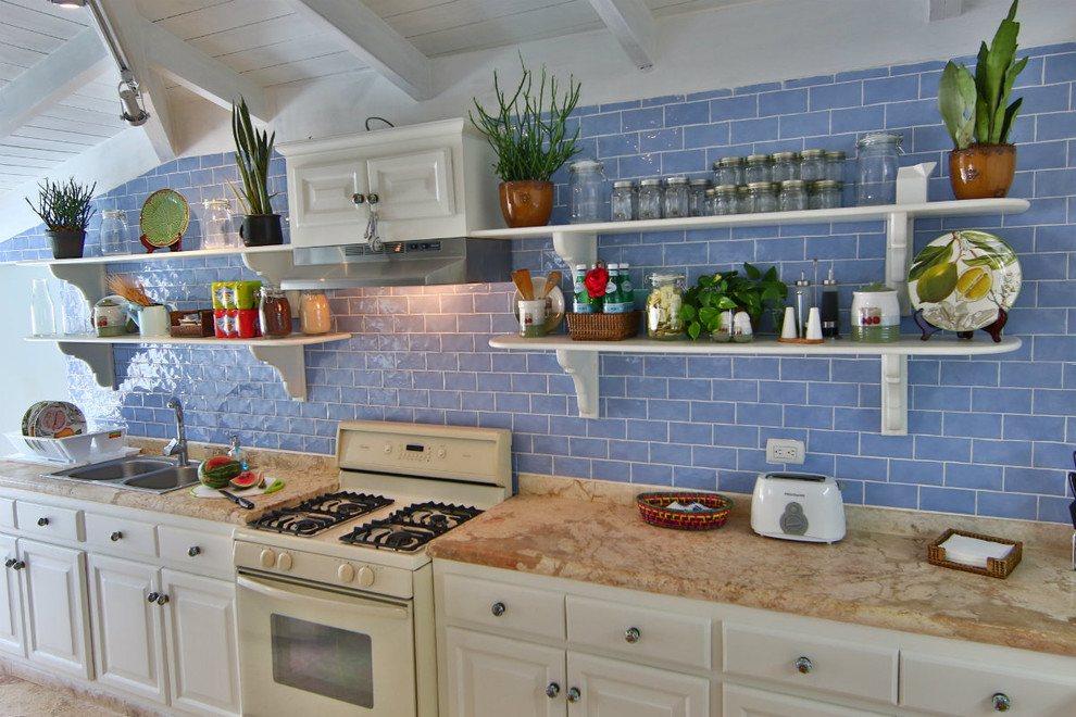 Inspiration for a small beach style l-shaped kitchen in Other with a double-bowl sink, white cabinets, limestone benchtops, blue splashback, ceramic splashback, white appliances, travertine floors and no island.