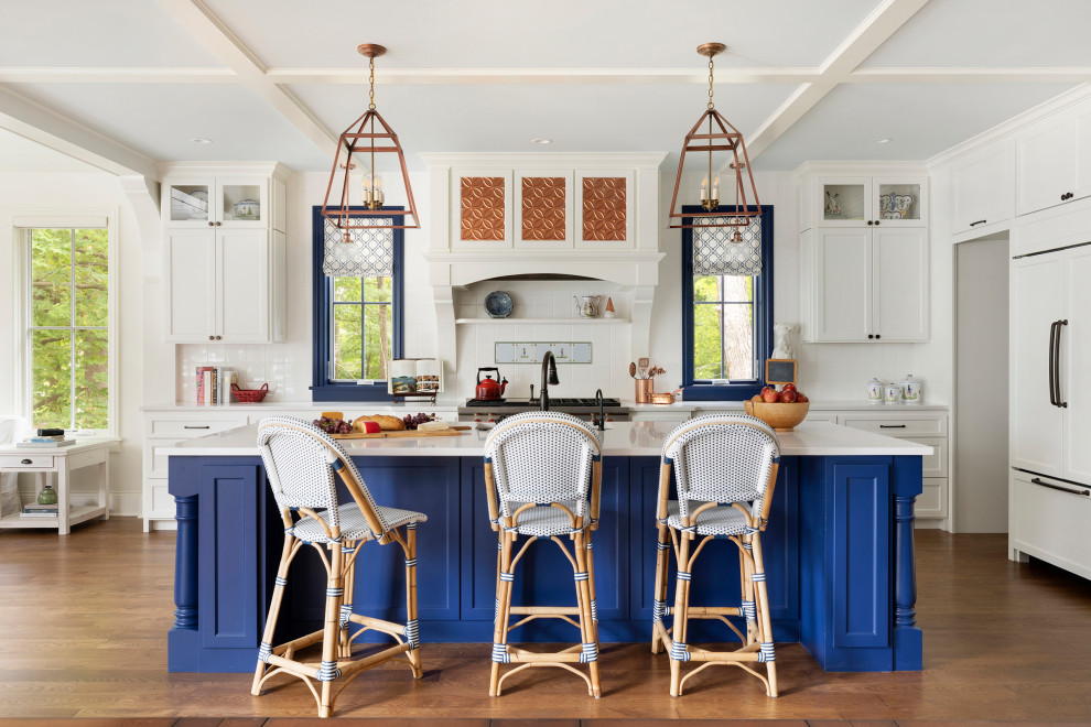 This is an example of a large beach style l-shaped kitchen/diner in Minneapolis with a submerged sink, shaker cabinets, yellow cabinets, engineered stone countertops, yellow splashback, ceramic splashback, integrated appliances, an island, yellow worktops, medium hardwood flooring, brown floors and a coffered ceiling.