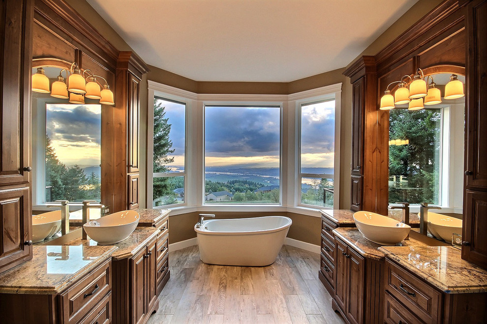 Photo of an expansive transitional master bathroom in Portland with raised-panel cabinets, brown cabinets, a freestanding tub, a curbless shower, a one-piece toilet, red tile, ceramic tile, brown walls, porcelain floors, a pedestal sink, granite benchtops, grey floor and an open shower.