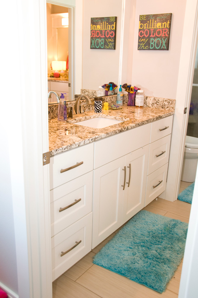 This is an example of a transitional kids bathroom in Cedar Rapids with an undermount sink, recessed-panel cabinets, white cabinets, granite benchtops, gray tile and porcelain tile.