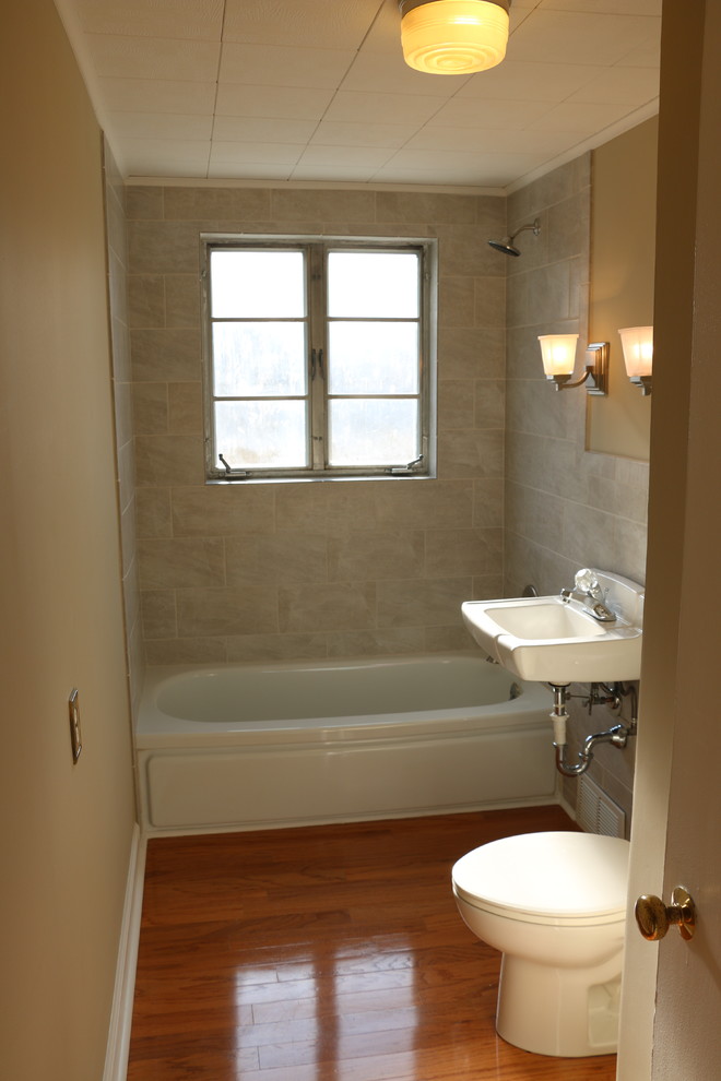 Example of a small classic kids' gray tile and ceramic tile light wood floor freestanding bathtub design with a two-piece toilet, beige walls and a pedestal sink