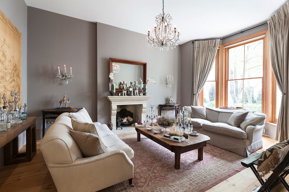 Design ideas for a large traditional formal enclosed living room in London with grey walls, laminate floors, a standard fireplace, a stone fireplace surround, no tv and brown floor.