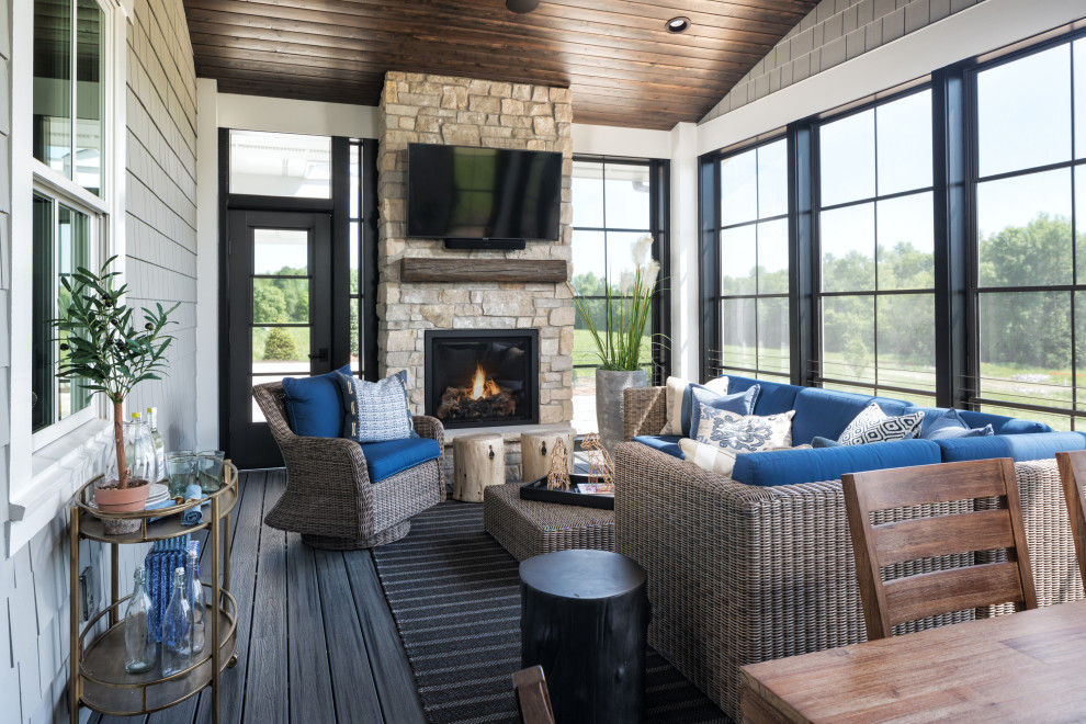 Inspiration for a transitional medium tone wood floor and brown floor sunroom remodel in Minneapolis with a standard fireplace, a stone fireplace and a standard ceiling
