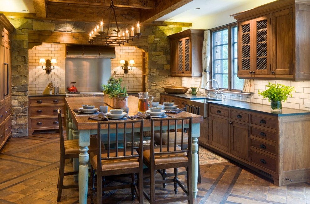 Inspiration for a large arts and crafts u-shaped eat-in kitchen in Denver with a farmhouse sink, recessed-panel cabinets, distressed cabinets, solid surface benchtops, white splashback, subway tile splashback, panelled appliances, ceramic floors, with island and brown floor.