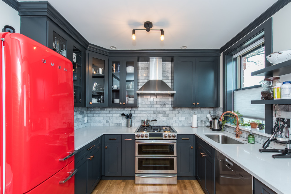 This is an example of a mid-sized transitional u-shaped kitchen in DC Metro with an undermount sink, quartzite benchtops, grey splashback, subway tile splashback, medium hardwood floors, no island, blue cabinets, coloured appliances and glass-front cabinets.