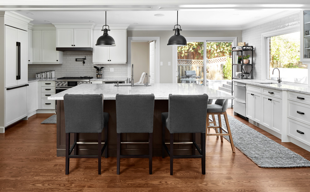Eat-in kitchen - transitional u-shaped medium tone wood floor and brown floor eat-in kitchen idea in Toronto with an undermount sink, shaker cabinets, white cabinets, quartz countertops, white backsplash, subway tile backsplash, stainless steel appliances, an island and gray countertops