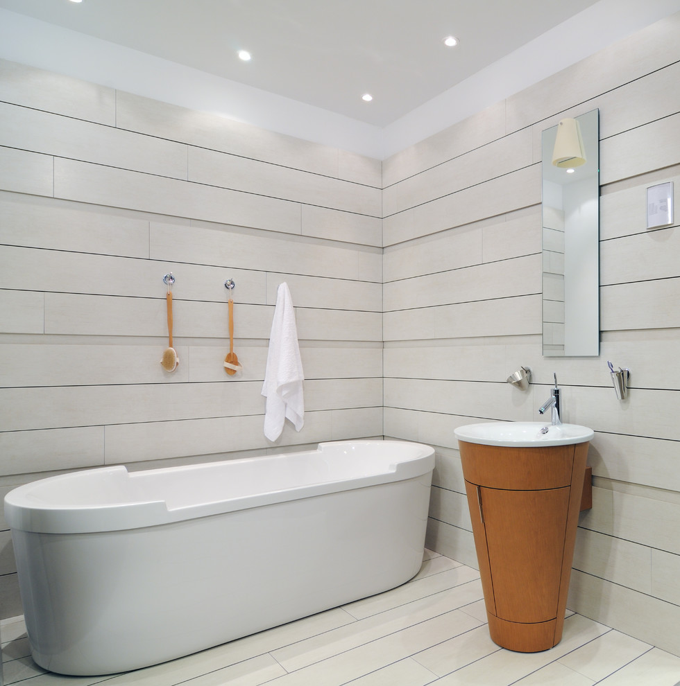 Design ideas for a large contemporary bathroom in Perth with a freestanding tub, beige tile, porcelain floors and a pedestal sink.