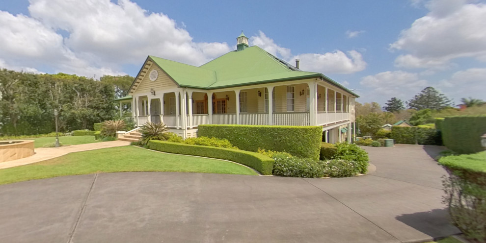 Large traditional two-storey yellow house exterior in Brisbane with wood siding, a gable roof and a metal roof.