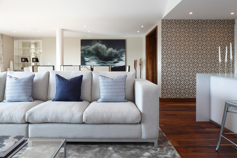 This is an example of a transitional open concept living room in London with beige walls and medium hardwood floors.