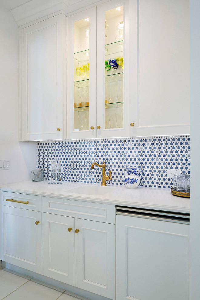Example of a mid-sized transitional l-shaped ceramic tile and beige floor open concept kitchen design in Miami with an undermount sink, recessed-panel cabinets, white cabinets, solid surface countertops, multicolored backsplash, mosaic tile backsplash, stainless steel appliances, an island and white countertops