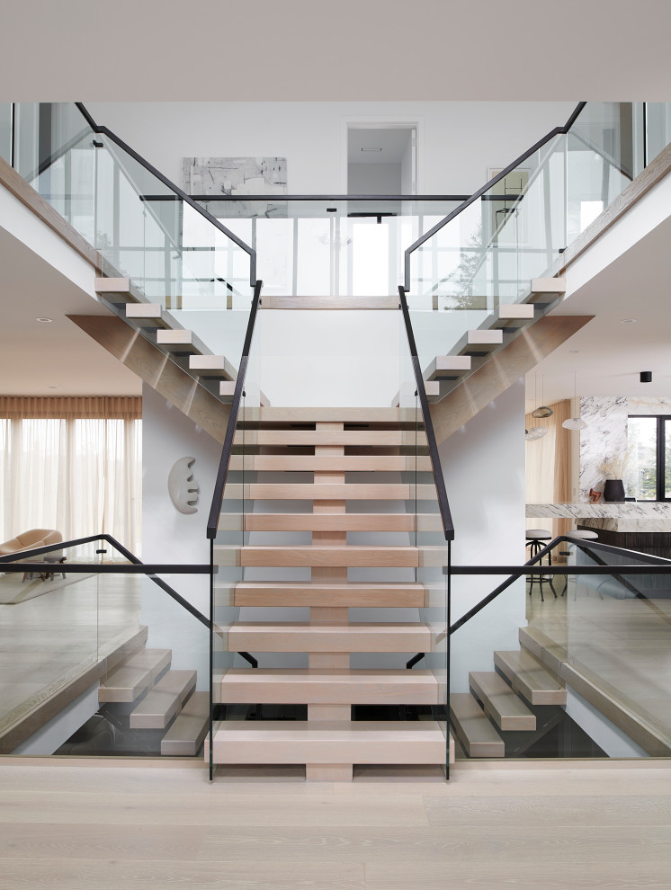 Пример оригинального дизайна: огромная лестница на больцах в стиле модернизм с деревянными ступенями и стеклянными перилами