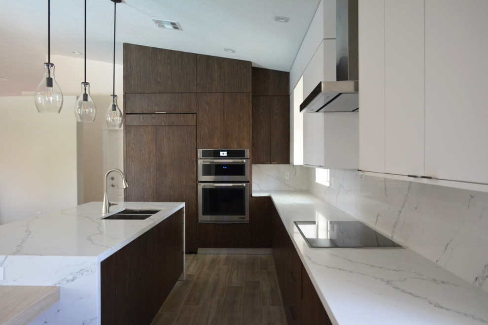 Example of a large transitional u-shaped medium tone wood floor and brown floor open concept kitchen design in Miami with a double-bowl sink, flat-panel cabinets, dark wood cabinets, quartzite countertops, white backsplash, marble backsplash, paneled appliances, an island and white countertops