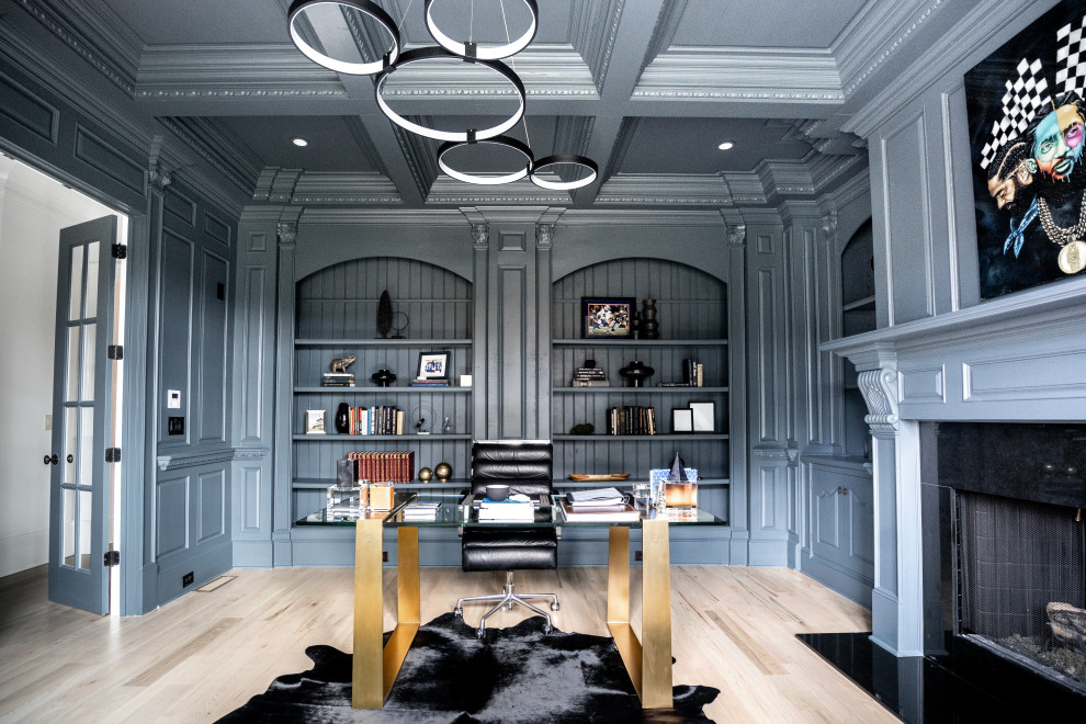 Modern inredning av ett stort arbetsrum, med grå väggar, ljust trägolv, en standard öppen spis, en spiselkrans i trä, ett fristående skrivbord och beiget golv