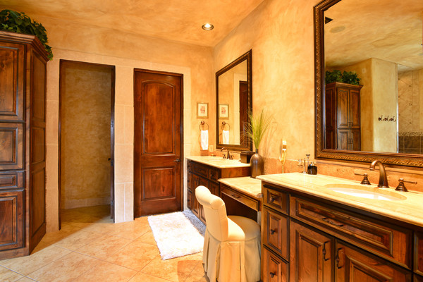 Design ideas for a large mediterranean master bathroom in Austin with a drop-in sink, dark wood cabinets, granite benchtops, a drop-in tub, a corner shower, a two-piece toilet, beige tile, stone tile, brown walls and travertine floors.