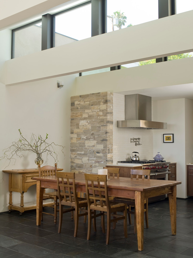 Photo of a mid-sized contemporary eat-in kitchen in Los Angeles with stainless steel appliances, an undermount sink, flat-panel cabinets, dark wood cabinets, quartzite benchtops, white splashback, subway tile splashback, slate floors, no island and grey floor.