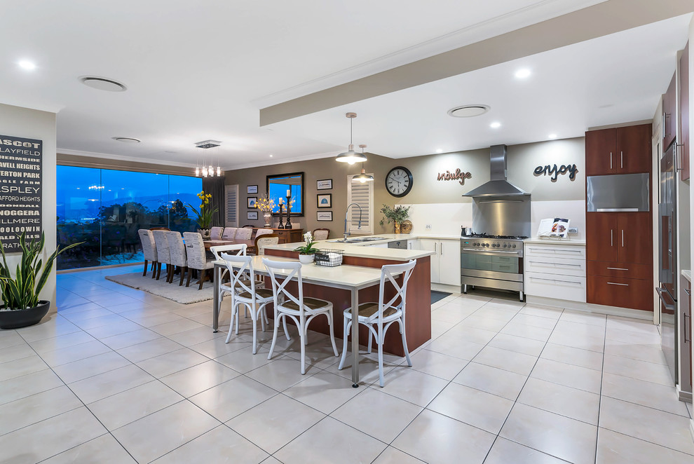 Transitional u-shaped eat-in kitchen in Brisbane with a drop-in sink, flat-panel cabinets, medium wood cabinets, white splashback, stainless steel appliances, grey floor and beige benchtop.