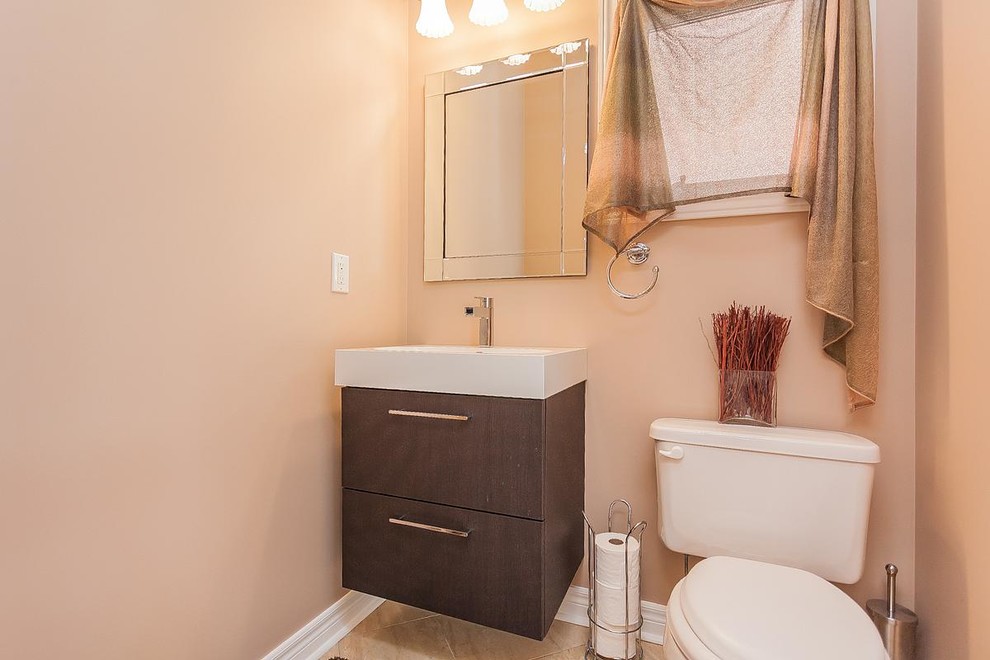 Design ideas for a small traditional powder room in Toronto with flat-panel cabinets, dark wood cabinets, a two-piece toilet, beige walls, ceramic floors and an integrated sink.