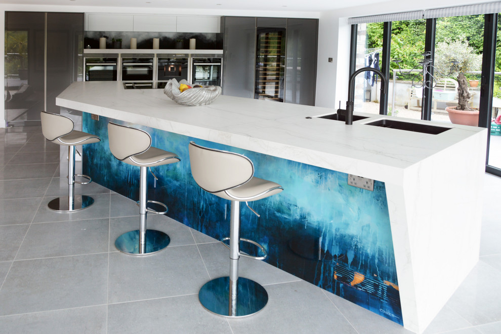 Foto på ett mycket stort funkis vit kök med öppen planlösning, med släta luckor, grå skåp, bänkskiva i kvarts, blått stänkskydd, glaspanel som stänkskydd och en köksö