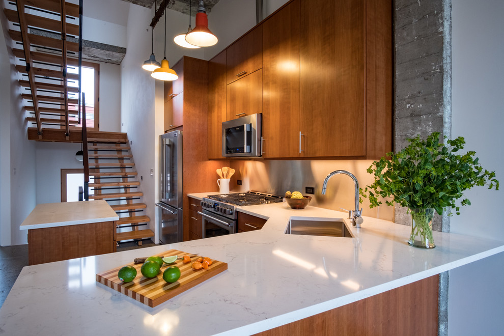 This is an example of a mid-sized modern l-shaped open plan kitchen in Portland with an undermount sink, shaker cabinets, medium wood cabinets, quartz benchtops, white splashback, stainless steel appliances, concrete floors, with island, grey floor and white benchtop.