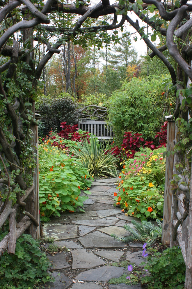This is an example of a traditional backyard garden in New York with natural stone pavers and a garden path.