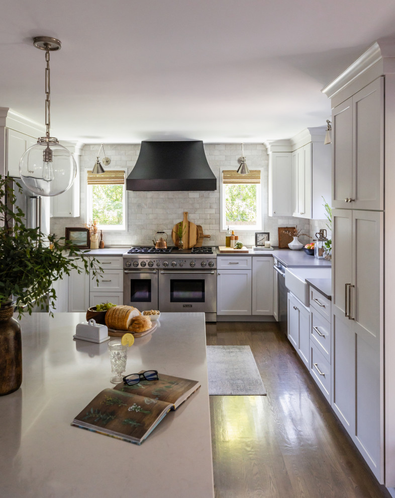 Open concept kitchen - mid-sized transitional u-shaped medium tone wood floor and brown floor open concept kitchen idea in Chicago with a farmhouse sink, shaker cabinets, white cabinets, quartz countertops, white backsplash, marble backsplash, stainless steel appliances, an island and gray countertops