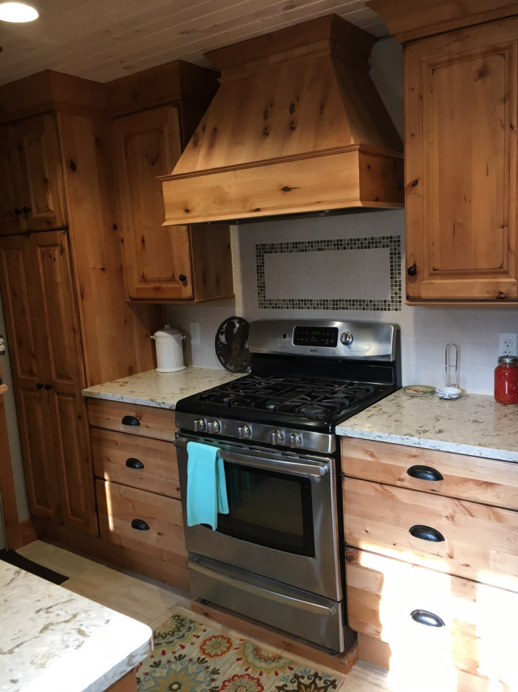 Enclosed kitchen - mid-sized rustic u-shaped enclosed kitchen idea in Detroit with a farmhouse sink, raised-panel cabinets, light wood cabinets, quartz countertops, beige backsplash, limestone backsplash, stainless steel appliances and no island