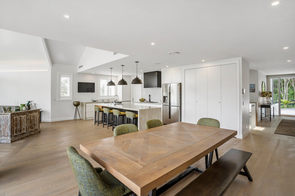 Large contemporary kitchen/dining combo in Auckland with white walls, light hardwood floors and beige floor.