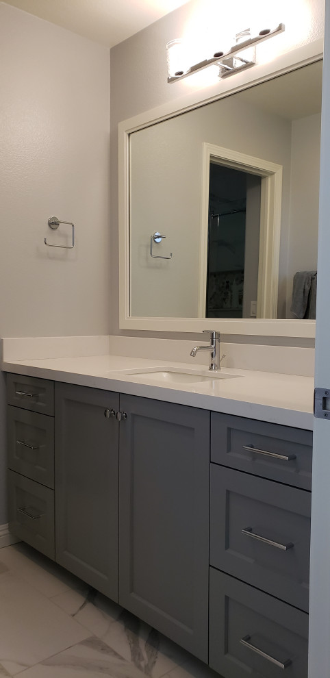 This is an example of a mid-sized transitional kids bathroom in Orange County with shaker cabinets, grey cabinets, grey walls, porcelain floors, an undermount sink, solid surface benchtops, white benchtops, a single vanity and a built-in vanity.