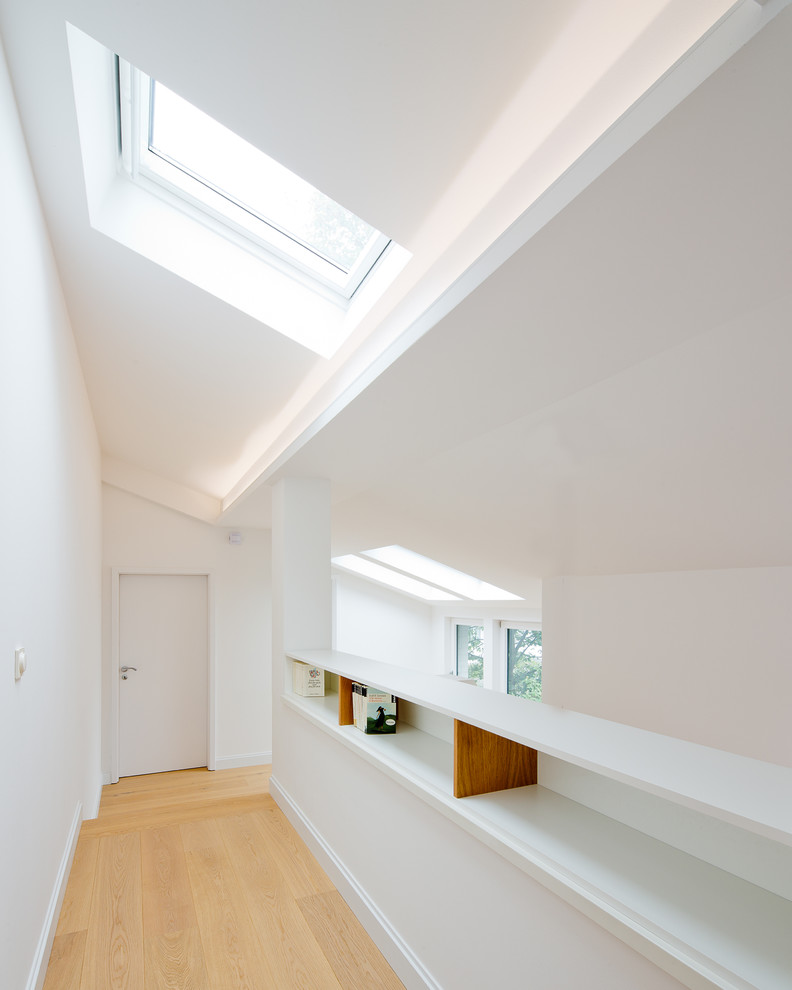 This is an example of a contemporary hallway in Dusseldorf with white walls and light hardwood floors.