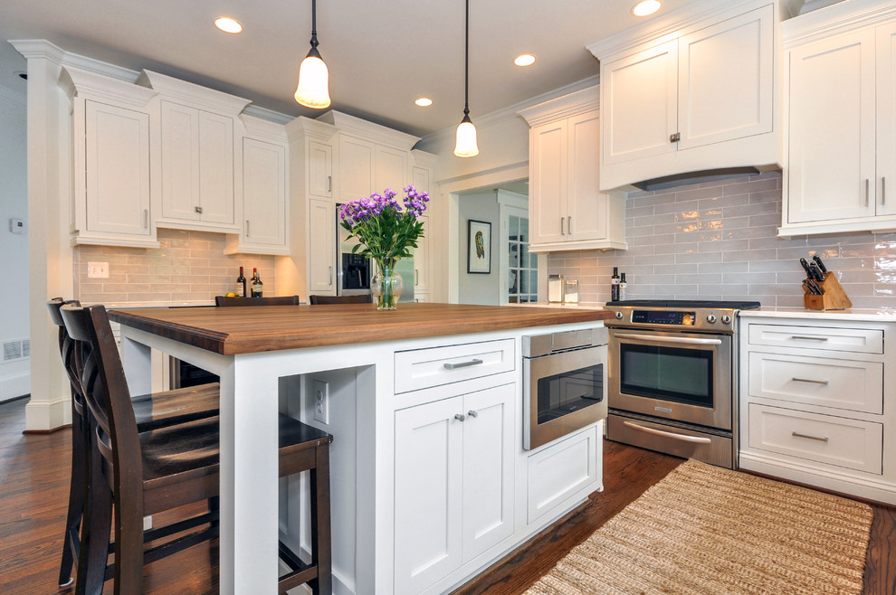 Inspiration for a mid-sized traditional l-shaped eat-in kitchen in Atlanta with a farmhouse sink, shaker cabinets, white cabinets, quartzite benchtops, grey splashback, subway tile splashback, stainless steel appliances, medium hardwood floors and with island.