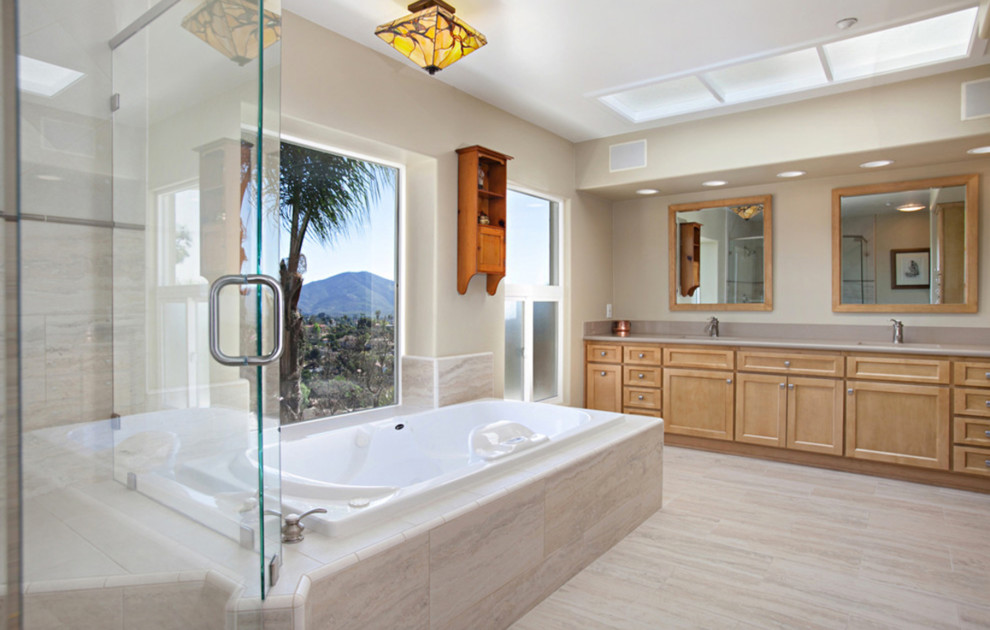 Design ideas for a large contemporary master bathroom in San Diego with shaker cabinets, light wood cabinets, a drop-in tub, a corner shower, a one-piece toilet, beige tile, gray tile, porcelain tile, beige walls, porcelain floors, an undermount sink, engineered quartz benchtops, beige floor and a hinged shower door.