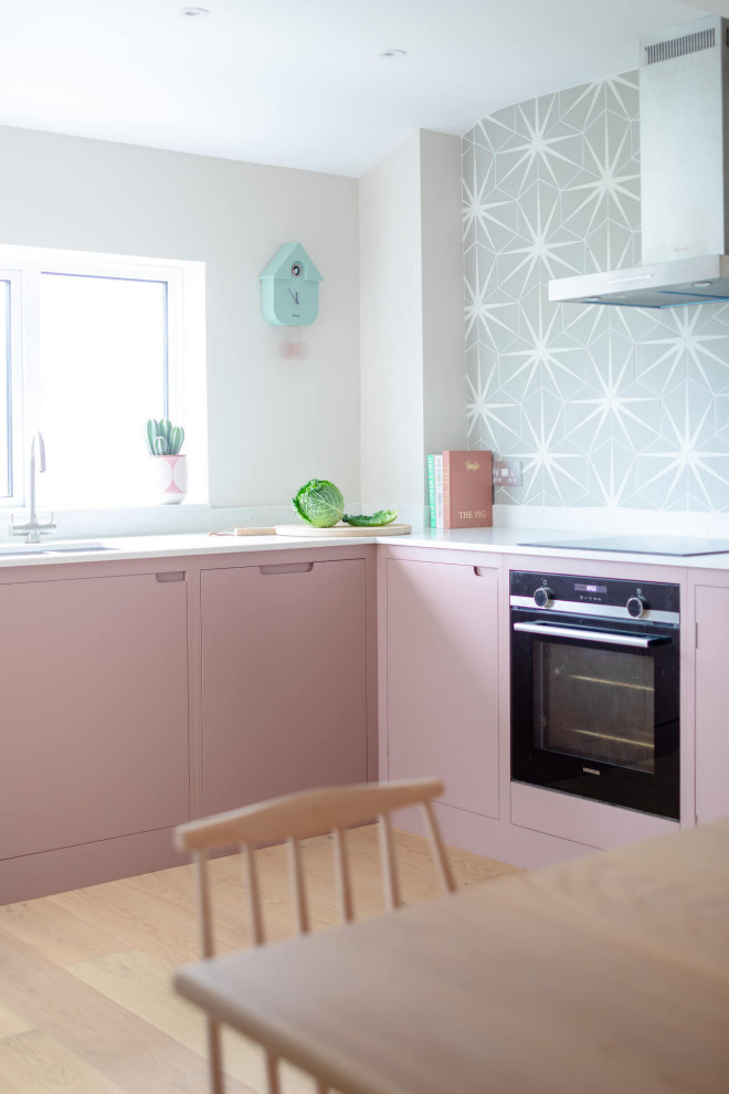 This is an example of a mid-sized scandinavian l-shaped eat-in kitchen in Other with flat-panel cabinets, pink cabinets, quartz benchtops, light hardwood floors, no island and white benchtop.