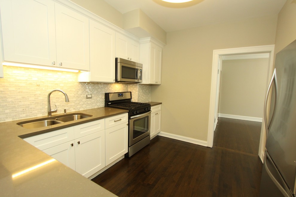Example of a small transitional u-shaped dark wood floor and brown floor enclosed kitchen design in Chicago with an undermount sink, recessed-panel cabinets, white cabinets, quartz countertops, white backsplash, mosaic tile backsplash, stainless steel appliances, no island and gray countertops