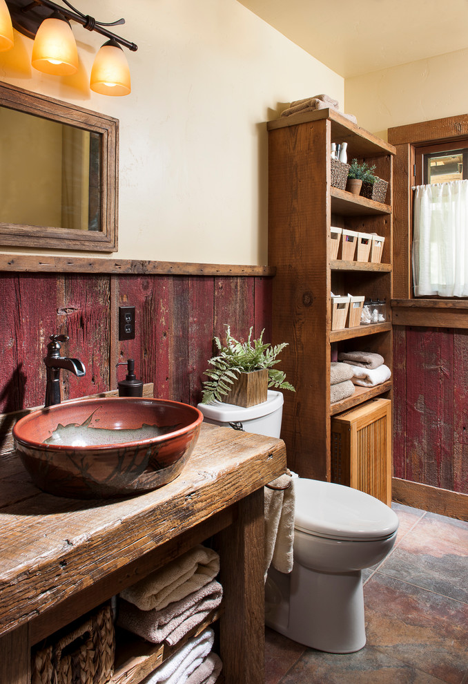 Inspiration for a small country bathroom in Other with open cabinets, brown cabinets, a two-piece toilet, beige walls, concrete floors, a vessel sink, wood benchtops and red floor.